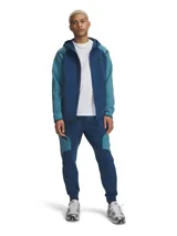Pantalón tipo jogging Under Armour de corte ajustado, confeccionado en tejido de doble punto elástico y transpirable. Presenta diseño bicolor en tonos azules, cintura elástica con cordón interno, bolsillos laterales abiertos y un bolsillo lateral con cierre. Incluye logo de la marca en la parte superior.