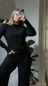 Pantalon de tejido de punto acanalado en color negro, con cintura elastizada y cordón ajustable. Presenta un corte cómodo y relajado.