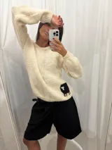 Sweater tejido color crudo de lana merino con dibujo de oveja negra en la espalda.