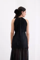Vestido largo de encaje negro con escote halter, cuerpo ajustado y falda fluida con tajo frontal.