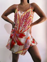 Vestido corto con estampado de hojas en tonos rojo, naranja, amarillo, lila y beige. Tiene tirantes finos y corte suelto.