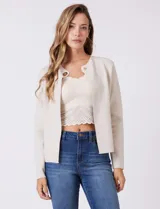 Cardigan tejido de punto color beige, con cuello a la base y cierre frontal mediante un botón metálico decorativo. Presenta mangas largas y corte recto.