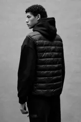 Chaleco negro acolchado con cuello alto y cierre frontal. Diseño sin mangas con bolsillos laterales con cierre y bolsillos interiores abiertos.
