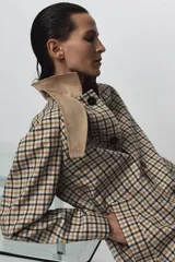 Trench reversible de Zara Woman Collection con diseño de cuadros en tonos beige, negro y tostado. Cuenta con cuello de solapa, cierre frontal con botones oscuros y bolsillos delanteros diagonales.