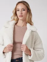 Tapado largo color blanco de tejido bouclé, marca Bcbg Maxazria. Cuenta con cuello de solapa amplia, cierre frontal con botones a presión internos, bolsillos funcionales y tajos laterales en el bajo. Forro interno a tono.