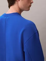 Buzo de felpa azul con cuello redondo, manga larga y corte regular. Presenta puños y dobladillo acanalados, con el logo y bordado 'Very' de Calvin Klein en el pecho.