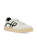 Championes de estilo urbano en color crema con detalles en negro. Presentan un diseño con logo lateral curvo, puntera de gamuza y suela de goma texturizada en tono natural.