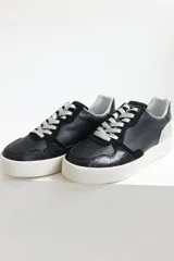 Zapatillas urbanas de cuero negro con cordones negros y suela blanca.