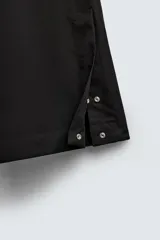 Pantalón de vestir gris oscuro, corte ancho (flare fit) y tiro alto, con bolsillos laterales y falsos bolsillos de vivo en la parte trasera. Presenta un cierre frontal con cremallera y gancho oculto, y botones a presión ocultos en el bajo.