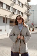 Saco oversize de tejido de punto en color rosa, con mangas caídas y detalles de bordado a mano en contraste en los bordes y costuras.