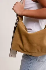 Bolso tipo hobo de gamuza color naranja quemado, con correa ancha de tela color bordó.