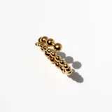 Anillo dorado de acero con diseño de borlas macizas de tamaño decreciente que se cruzan en el frente.