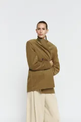 Blazer oversize de pana con cuello solapa y manga larga. Presenta cierre frontal cruzado con botones, bolsillos delanteros y forro interior a tono.