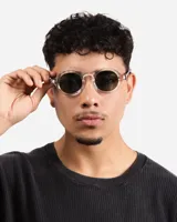 Lentes de sol redondos con montura transparente con detalles moteados y lentes oscuros.