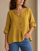 Blusa de lino color mostaza con escote en V y botones frontales. Cuenta con mangas largas remangables con presilla y botón, y diseño de corte holgado.