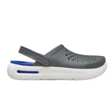 Zuecos Crocs modelo InMotion, con diseño deportivo. Presentan una parte superior gris con perforaciones, correa trasera pivotante, suela blanca gruesa y detalles en azul en la plantilla y la entresuela.