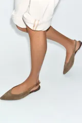Zapato plano tipo destalonado confeccionado en serraje, con diseño de punta fina y tira trasera ajustable con hebilla metálica.