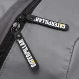 Mochila gris Caterpillar modelo Tokyo Urban Backpack, fabricada en poliéster. Cuenta con compartimento principal, bolsillos laterales de malla negra, asa superior y detalles de la marca en color amarillo y negro.