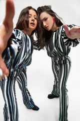 Pantalón de corte semi oxford con estampado de rayas verticales en tonos blanco, negro y verde. Presenta aberturas en el ruedo y está confeccionado en tela crepe.