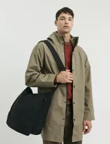 Gabardina con capucha de corte recto y largo medio. Cuenta con cierre frontal engomado, cartera con botones a presión, bolsillos laterales y tejido repelente al agua y al viento.