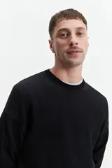 Buzo de punto oversize color negro, con escote redondo y puños.