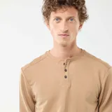 Camiseta de manga larga en color beige, con cuello panadero y cierre frontal de dos botones.