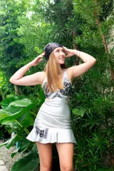 Vestido corto negro con estampado de plumas doradas, escote en V, breteles finos cruzados en la espalda, cut-outs laterales y volado en el ruedo.