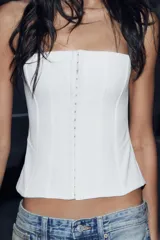 Top tipo corset de escote recto y hombros descubiertos, con cierre frontal mediante ganchos metálicos y costuras verticales estructuradas.
