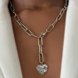 Collar plateado con cadena de eslabones grandes y dije de corazón con estrellas.