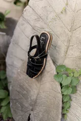 Sandalias de cuero con tiras entrecruzadas, suela plana y hebilla lateral.