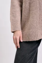Cardigan de punto en color beige, con escote en V, cierre frontal de botones y mangas largas con puños acanalados.