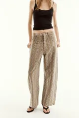 Pantalón de tiro medio en color marrón con diseño de animal print y aplicaciones de brillos en contraste. Cuenta con cinco bolsillos, presillas para cinturón y cierre frontal con cremallera y botón metálico.