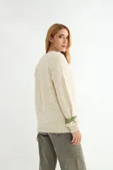 Buzo de tejido de punto con textura suave, color celeste pastel con efecto jaspeado. Presenta cuello redondo, mangas largas con terminación en puño y un diseño de canalé en la parte superior del pecho.