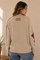 Buzo de punto color beige con diseño geométrico y abstracto en tonos rojo, azul y marrón, de corte holgado, cuello redondo y mangas largas.