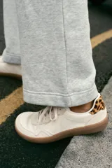 Zapatillas deportivas barefoot de color blanco con detalles en beige y suela de goma marrón. Presentan cordones blancos y detalle de estampado animal print de leopardo en la talonera.