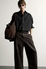 Pantalón barrel fit de corte ancho color marrón, confeccionado en mezcla de algodón y lino. Presenta bolsillos frontales, bolsillos traseros de vivo y cierre frontal con cremallera y botón.