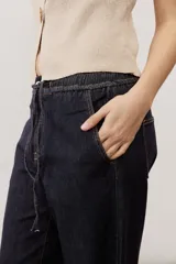 Jean azul oscuro de corte wide leg, con cintura elástica ajustable mediante cordón y bolsillos laterales.
