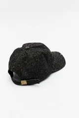 Gorra de béisbol con estampado animal print en tonos marrones y negros, con detalles desgastados y hebilla metálica ajustable en la parte trasera.