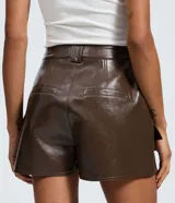 Short pollera de tiro medio confeccionado en poliuretano con acabado brillante. Presenta diseño de corte recto con bolsillos frontales tipo cargo con solapa y cierre frontal con cremallera.