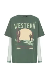 Remera de algodón color verde con estampado frontal estilo western, cuello redondo y mangas cortas. Incorpora mangas largas ajustadas de tul integradas debajo de las mangas cortas.