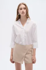 Short pollera color rosa viejo, de diseño cruzado tipo envolvente con detalle de botones laterales.