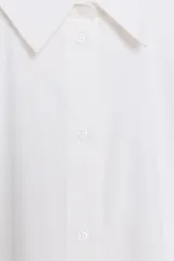 Camisa de cuello solapa y manga larga abullonada con puños ajustados. Presenta un cierre frontal con botones y un corte holgado.