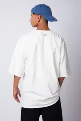 Remera de corte oversize, color blanco, con cuello redondo y mangas cortas amplias.