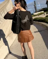 Blusa negra de corte holgado con mangas largas abullonadas y bordado de cebra en la espalda.