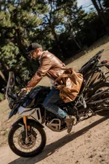 Bolso de cuero hecho a mano en color tostado, con diseño amplio y funcional. Presenta cierre superior, bolsillo frontal con cremallera, asas de mano reforzadas y una correa larga ajustable y desmontable.