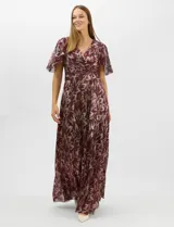 Vestido largo de fiesta con diseño cruzado, escote en V y mangas cortas acampanadas. Presenta un acabado plisado con estampado floral metalizado, drapeado lateral en la cintura y falda amplia con caída fluida.