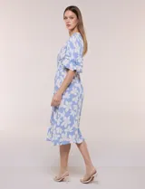 Vestido midi de calce holgado y caída fluida con escote en V cruzado, cintura elastizada fruncida y mangas cortas con volados superpuestos. Cuenta con un diseño estampado de flores grandes en tonos amarillo, blanco, azul marino y verde.