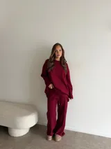 Conjunto de dos piezas color tostado, compuesto por un buzo de cuello redondo con mangas largas y hombros caídos, y un pantalón de corte recto con cintura elástica y cordón ajustable.