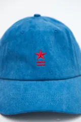 Gorra clásica de denim lavado azul con bordado rojo de una estrella y líneas en el frente, y visera curva.