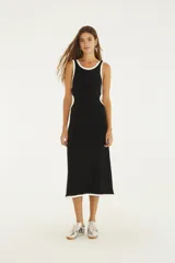 Vestido midi bicolor negro con detalles en blanco en el escote, sisas, aberturas laterales y ruedo. Diseño sin mangas con escote redondo y aberturas cut-out a los lados.